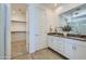 Spacious bathroom with dual sinks, white cabinetry, and a walk-in closet at 16381 W Weeping Willow Rd, Surprise, AZ 85387