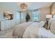 Bright bedroom features a decorative mirror, neutral tones and a large window at 16381 W Weeping Willow Rd, Surprise, AZ 85387