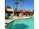Stunning community pool with sunshades and lounge seating surrounded by tall palm trees on a sunny day at 17718 N Desert Flower Trl, Surprise, AZ 85374