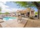 Lush backyard featuring a sparkling pool, covered patio, and well-manicured landscaping for outdoor living at 19537 E Thornton Rd, Queen Creek, AZ 85142
