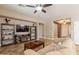 Comfortable living room with a ceiling fan, decorative shelves, a large TV, and a cozy fireplace at 19537 E Thornton Rd, Queen Creek, AZ 85142