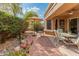 Landscaped backyard with patio seating, shaded by a leafy tree and umbrella at 19874 N 90Th Ave, Peoria, AZ 85382
