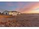 Wide shot of property with home, shed, white horse fence, and open field at dusk at 25450 W Pueblo Ave, Buckeye, AZ 85326