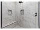 Walk-in shower boasts elegant marble tiling, a built-in bench, and niche shelves at 25450 W Pueblo Ave, Buckeye, AZ 85326