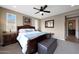 This bedroom features a dark wood bed frame, a ceiling fan, and neutral-colored walls and carpet at 3359 E Penedes Dr, Gilbert, AZ 85298