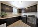 Large laundry room with dark cabinets, washer and dryer, and tile flooring at 3359 E Penedes Dr, Gilbert, AZ 85298