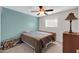 Cozy bedroom featuring light teal wall, ceiling fan, and window providing ample natural light at 3422 W Poinsettia Dr, Phoenix, AZ 85029