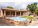 Backyard showcasing a custom pool with rock features and a covered patio connected to the house at 345 S Buena Vista Ave, Gilbert, AZ 85296