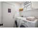 Bright laundry room featuring a washer, dryer, storage shelf, and access to exterior at 4728 N 92Nd Ave, Phoenix, AZ 85037
