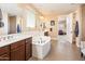 Bright bathroom featuring a soaking tub, dual sinks, and an open doorway leading into the bedroom at 4836 S Covalent Ln, Mesa, AZ 85212