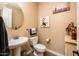 This bathroom has a pedestal sink, toilet, round mirror, and decorative art at 4836 S Covalent Ln, Mesa, AZ 85212