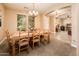 A dining room features a wooden table with seating for six people under an elegant chandelier at 4836 S Covalent Ln, Mesa, AZ 85212