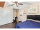 Comfortable bedroom with a ceiling fan, sliding closet doors, and a bed with blue bedding and wooden floors at 5025 N 20Th Ave, Phoenix, AZ 85015