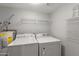 Bright laundry room featuring white appliances, overhead shelving, and a water heater at 5621 N 79Th St, Scottsdale, AZ 85250