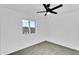 This bedroom features neutral carpeting, white walls and trim, a ceiling fan, and neighborhood views at 607 E Holmes Ave, Mesa, AZ 85204