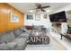Cozy living room features wood paneling, fan, gray sectional couch, and Saints blanket at 6445 W Windsor Blvd, Glendale, AZ 85301