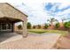 Backyard featuring a covered patio, manicured lawn, mature trees, and a brick-paved walkway at 7342 S Debra Dr, Gilbert, AZ 85298
