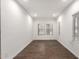 An empty room featuring dark wood floors and white walls. Two windows with blinds let in natural light at 7342 S Debra Dr, Gilbert, AZ 85298