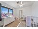 Bright bedroom with a white ceiling fan, crib, window and a door to the bathroom at 7949 W Pershing Ave, Peoria, AZ 85381