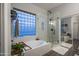 Bright bathroom showcasing tub beneath a glass block window and a walk-in shower with glass doors at 8544 W Mary Ann Dr, Peoria, AZ 85382