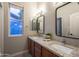 Bathroom featuring wood cabinets, dual sinks, granite countertops, and modern light fixtures at 8544 W Mary Ann Dr, Peoria, AZ 85382