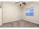 Empty bedroom with neutral walls, carpet, a ceiling fan, and a window overlooking the neighborhood at 8544 W Mary Ann Dr, Peoria, AZ 85382