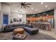 Open-concept living room featuring a gray sectional couch, modern lighting, and a kitchen with stainless steel appliances at 8544 W Mary Ann Dr, Peoria, AZ 85382