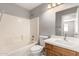 Bright bathroom with white tile, shower-tub, white toilet, sink and a wooden cabinet at 8614 W Shaw Butte Dr, Peoria, AZ 85345