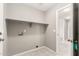 Neutral-toned laundry room featuring a built-in shelf, washer/dryer hookups, and tiled flooring at 8614 W Shaw Butte Dr, Peoria, AZ 85345