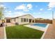 Beautiful backyard featuring travertine decking, a pool, and synthetic grass at 9612 E Rainbow Ave, Mesa, AZ 85212