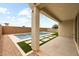 Backyard view of a pool area with travertine decking, synthetic grass accents, and privacy wall at 9612 E Rainbow Ave, Mesa, AZ 85212