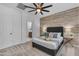 Comfortable bedroom boasts a wood accent wall, soft carpet, ceiling fan, and an ensuite bathroom at 9853 E Solstice Ave, Mesa, AZ 85212