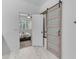 Hallway with a sliding barn door entry leading to a well-lit bedroom with a ceiling fan at 9853 E Solstice Ave, Mesa, AZ 85212