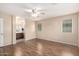 Large bedroom with laminate flooring, a ceiling fan, large window and a partial view of an ensuite bathroom at 10 N 87Th Dr, Tolleson, AZ 85353