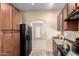 Kitchen featuring wood cabinets and black appliances and an open archway to the living room at 10 N 87Th Dr, Tolleson, AZ 85353