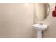 Elegant powder room features pedestal sink and oval mirror; a charming and functional space at 10 N 87Th Dr, Tolleson, AZ 85353