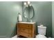 This powder room has a wooden vanity, green walls, and a round framed mirror at 10156 E Talon Ave, Mesa, AZ 85212