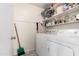 Bright laundry room features white washer and dryer, storage shelf, and gray look flooring at 1130 W Kingbird Dr, Chandler, AZ 85286