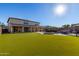 Expansive backyard with a large artificial turf area, pool with a rock waterfall, and a covered patio at 11844 W Nadine Way, Peoria, AZ 85383