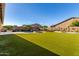 Large backyard featuring artificial turf, pool with rock waterfall feature, and ample space for outdoor activities at 11844 W Nadine Way, Peoria, AZ 85383