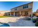Large covered patio overlooking the travertine-tiled backyard with a built-in fire pit, outdoor kitchen, and synthetic grass at 11844 W Nadine Way, Peoria, AZ 85383