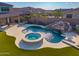 Inviting backyard with travertine tile, pool, spa, rock waterfall, and synthetic grass at 11844 W Nadine Way, Peoria, AZ 85383