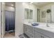 Bathroom with double vanity, large mirror, and walk-in shower with glass door at 11844 W Nadine Way, Peoria, AZ 85383