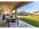 Spacious covered patio with dining area, grill, and a view of the backyard pool and waterfall feature at 11844 W Nadine Way, Peoria, AZ 85383