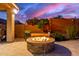Cozy fire pit surrounded by lush greenery, creating a warm and inviting outdoor space for gatherings under a purple sky at 11844 W Nadine Way, Peoria, AZ 85383