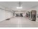 Spacious garage with epoxy flooring, overhead storage racks, service door, and a side by side refrigerator at 11844 W Nadine Way, Peoria, AZ 85383