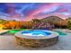 Beautiful backyard pool with stone waterfall and hot tub for ultimate relaxation under a dramatic twilight sky at 11844 W Nadine Way, Peoria, AZ 85383