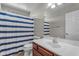 Bright bathroom features a white vanity, toilet, mirror and a blue and white striped shower curtain at 1237 W Agrarian Hills Dr, San Tan Valley, AZ 85143