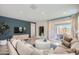 Cozy living room featuring a blue accent wall, comfortable seating, and a sliding glass door to the patio at 15791 W Kendall St, Goodyear, AZ 85338