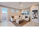 Comfortable living room features a white sectional sofa, coffee table, and natural light from a nearby door at 15791 W Kendall St, Goodyear, AZ 85338